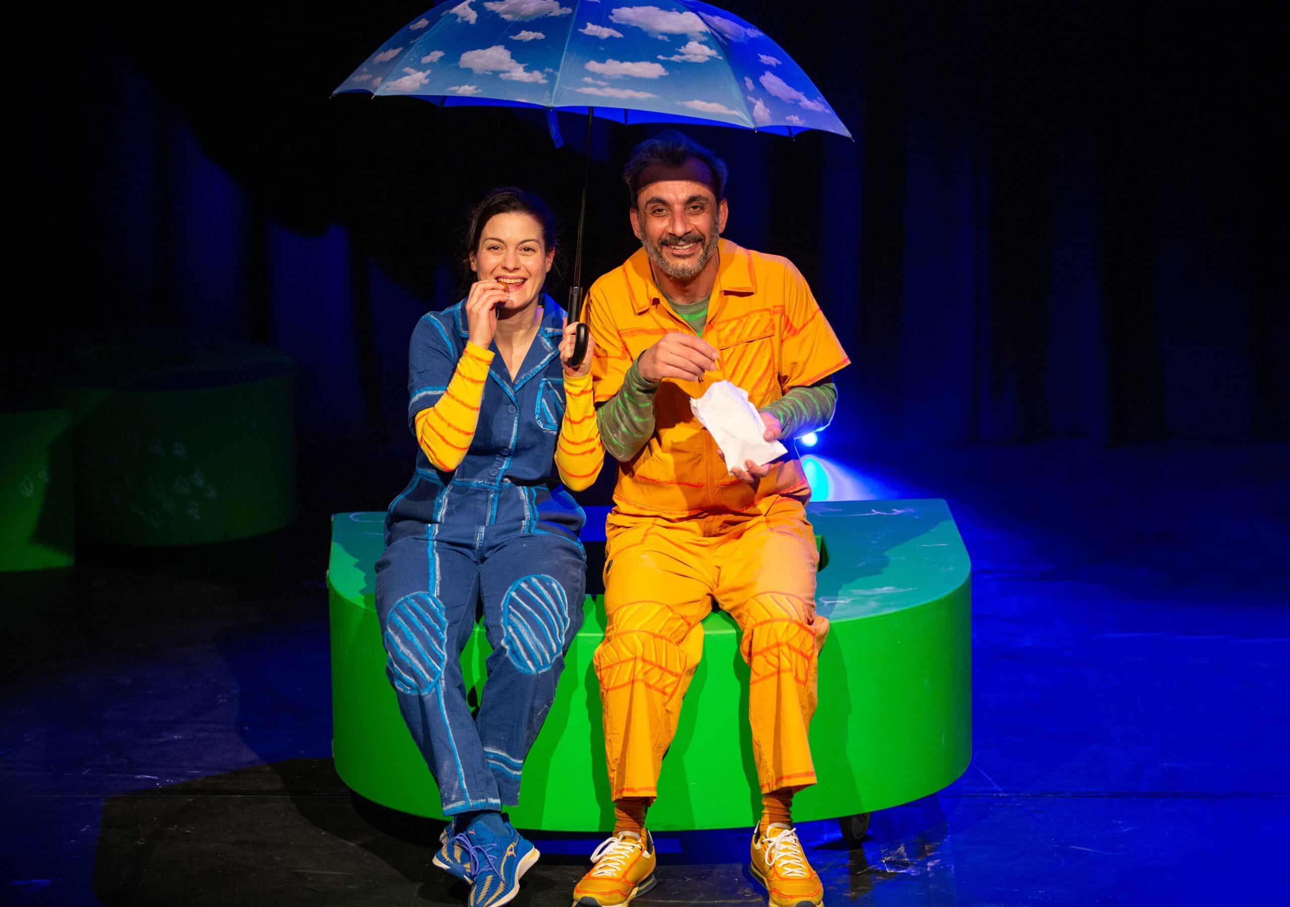 zwei Menschen sitzen nebeneinander unter einem Regenschirm