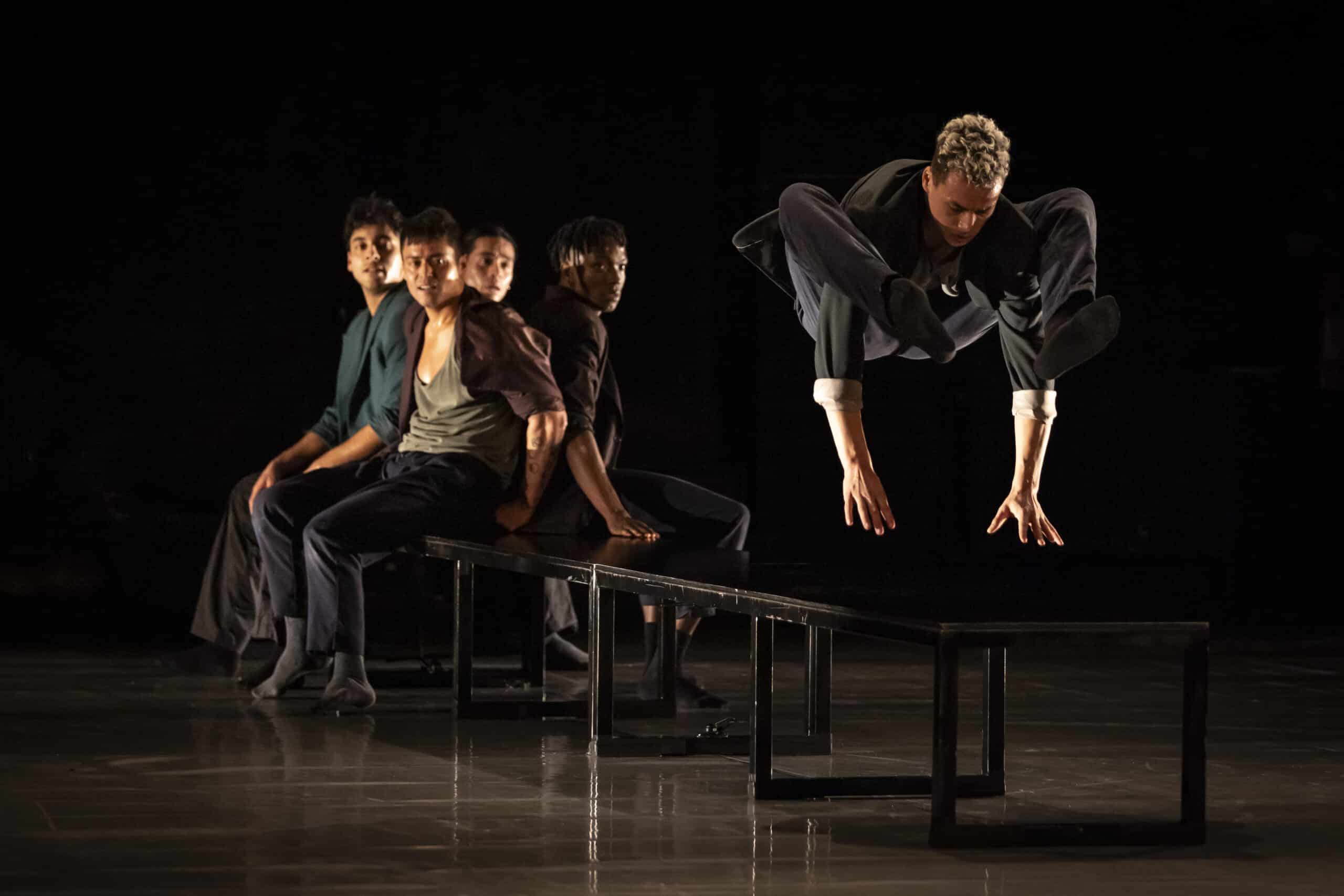 Tänzer sitzen und tanzen auf einer schwarzen Bank