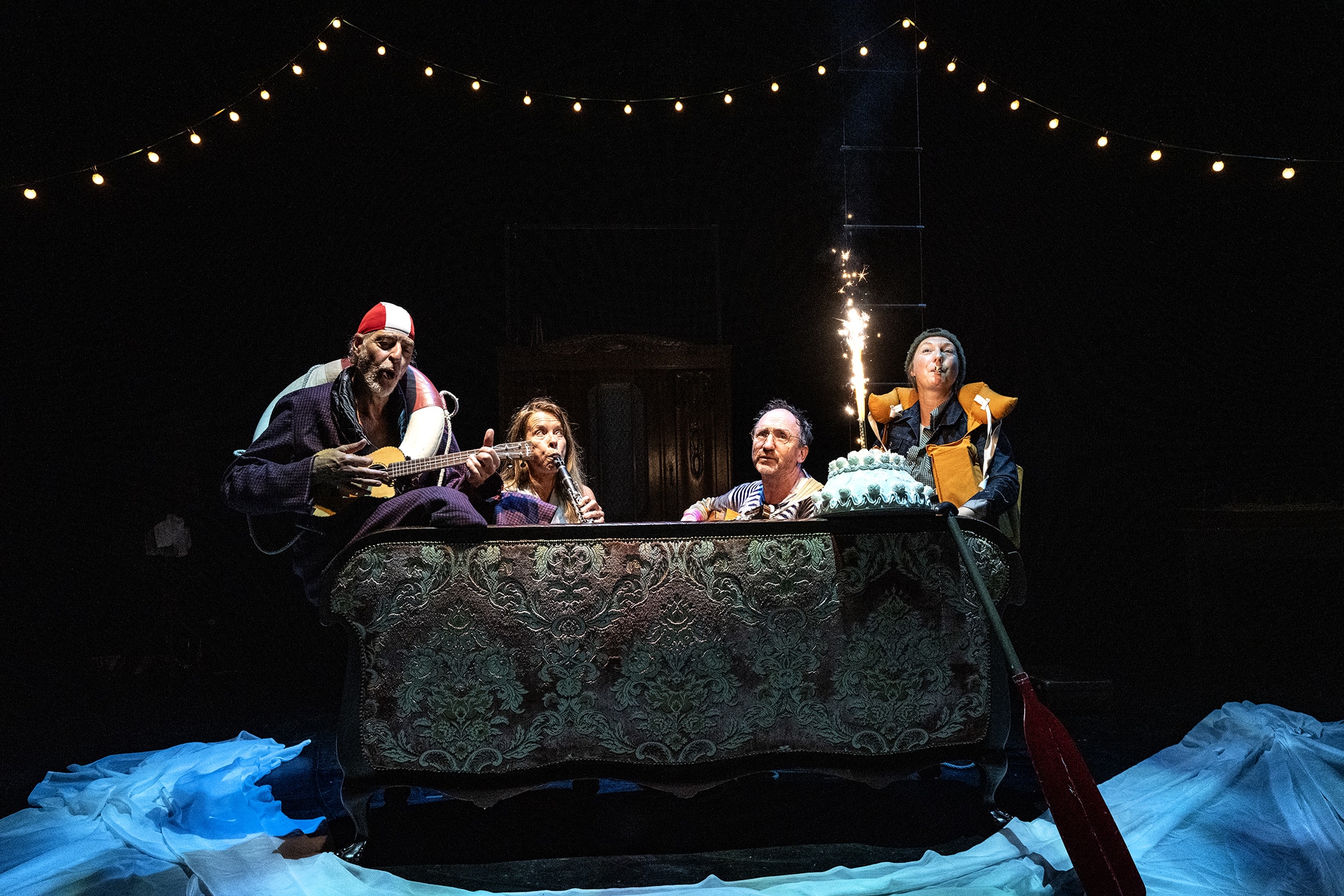 Bühnenfoto Freddie, die ganze Familie sitzt auf dem Sofa, es wird Musik gespiel, auf der Torte brennt eine Kerze