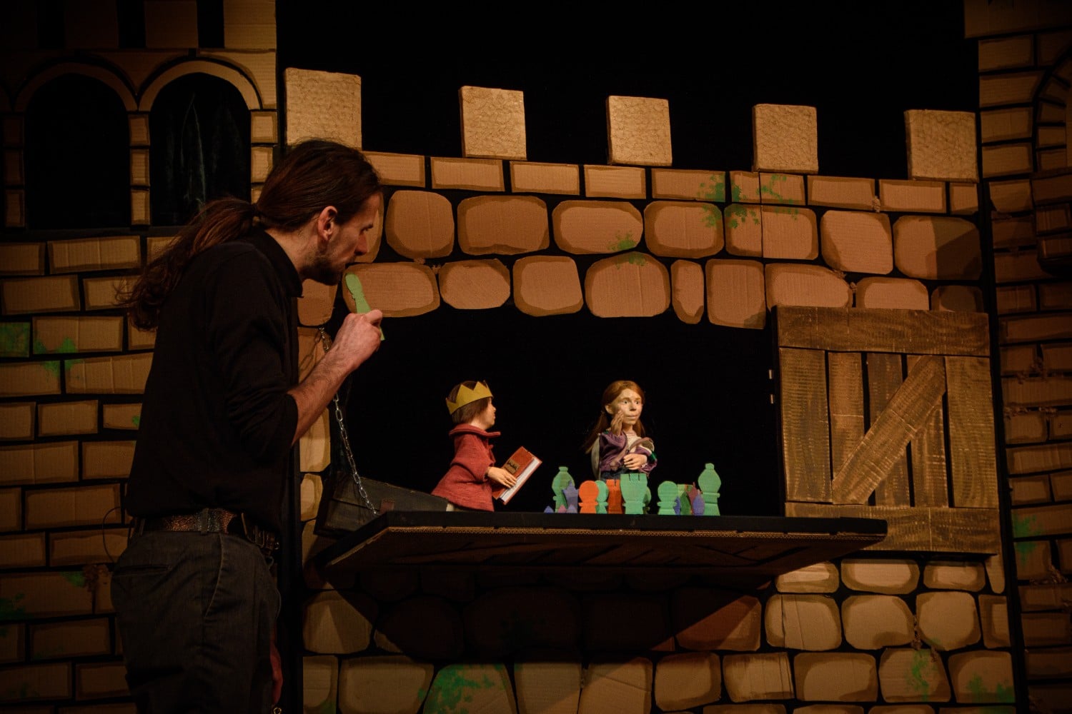 Eine Schlossmauer aus Pappe, darin spielen zwei Handpuppen, davor ein Mensch