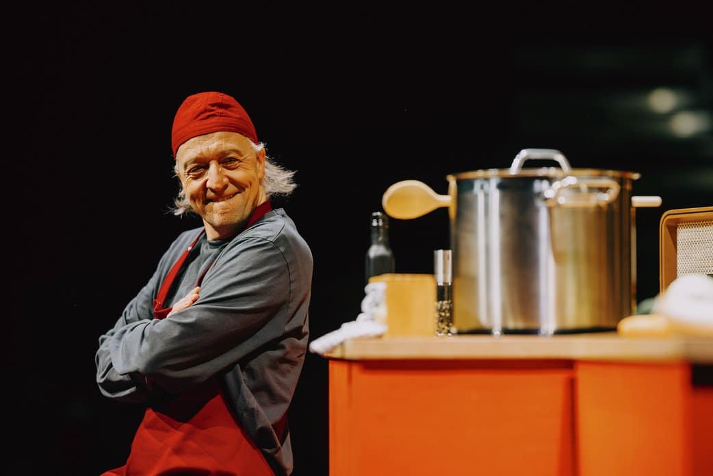 Mann in Kochsachen, im Vordergrund ein Kochtopf