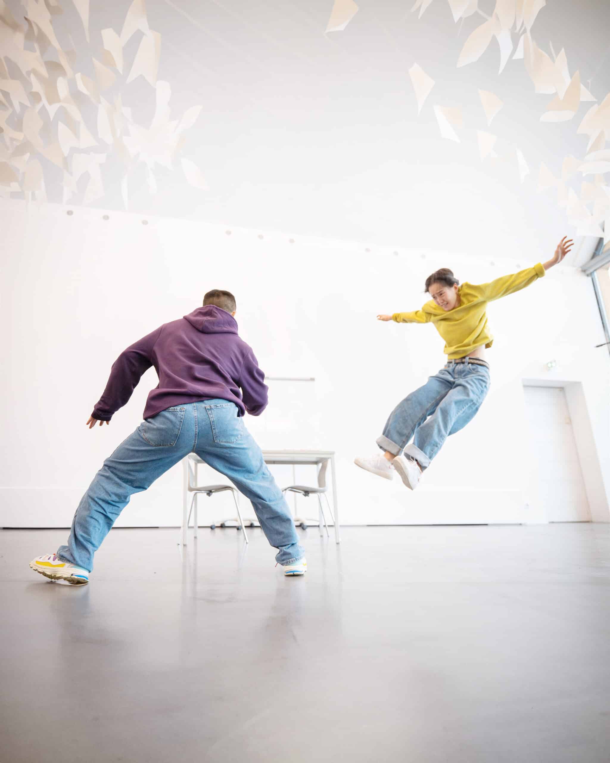 zwei tanzende Personen, eine steht breitbeinig, die andere scheint in der Luft zu hängen