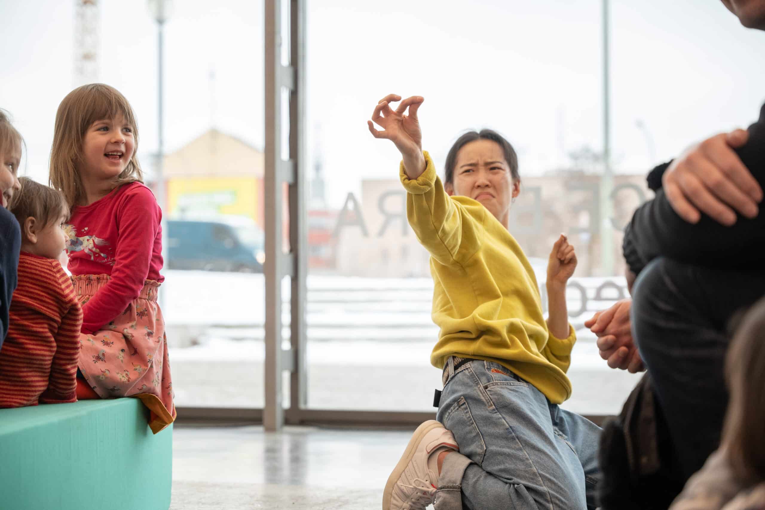 eine Tänzerin kniet auf dem Boden, sie schein zwischen den spitzen Fingern etwas zu halten