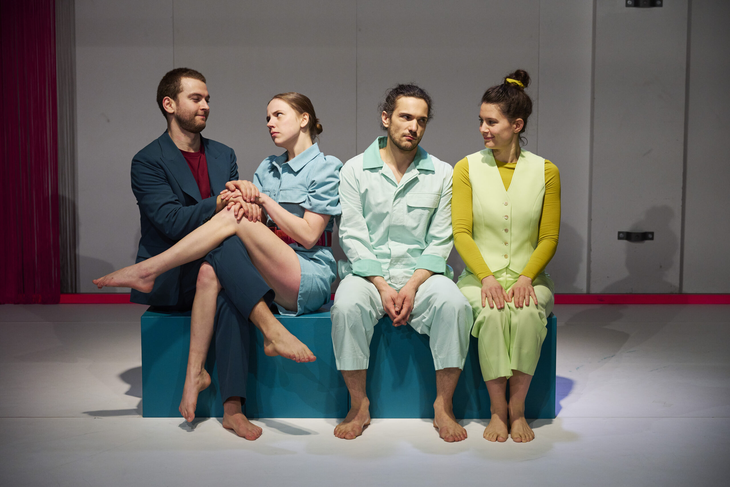 4 Menschen sitzen nebeneinander auf blauen Kisten