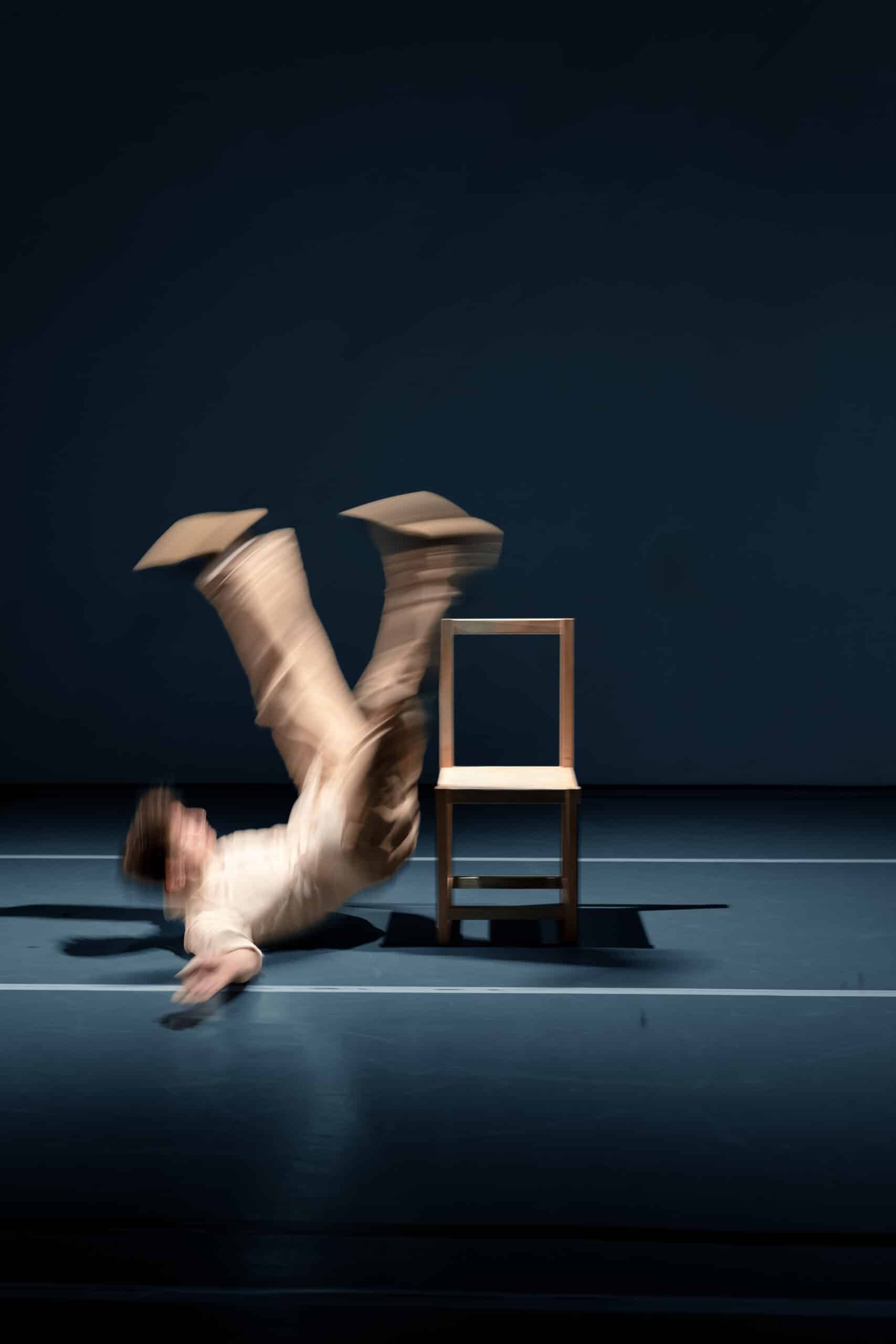 Tänzer in Bewegung, er fällt neben einem Stuhl zu Boden